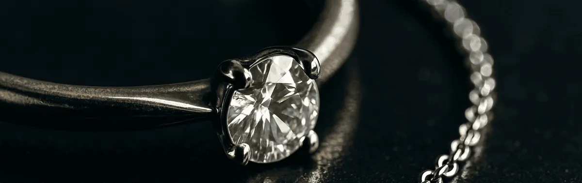 Schmuckfotografie im Studio: Goldring mit funkelndem Diamant und Silberkette auf dunklem Untergrund, reflexionskontrolliert ausgeleuchtet
