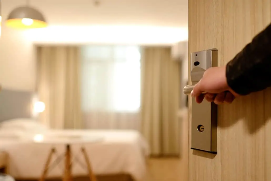 Eine Person hält eine Türklinke in einem Hotelzimmer.