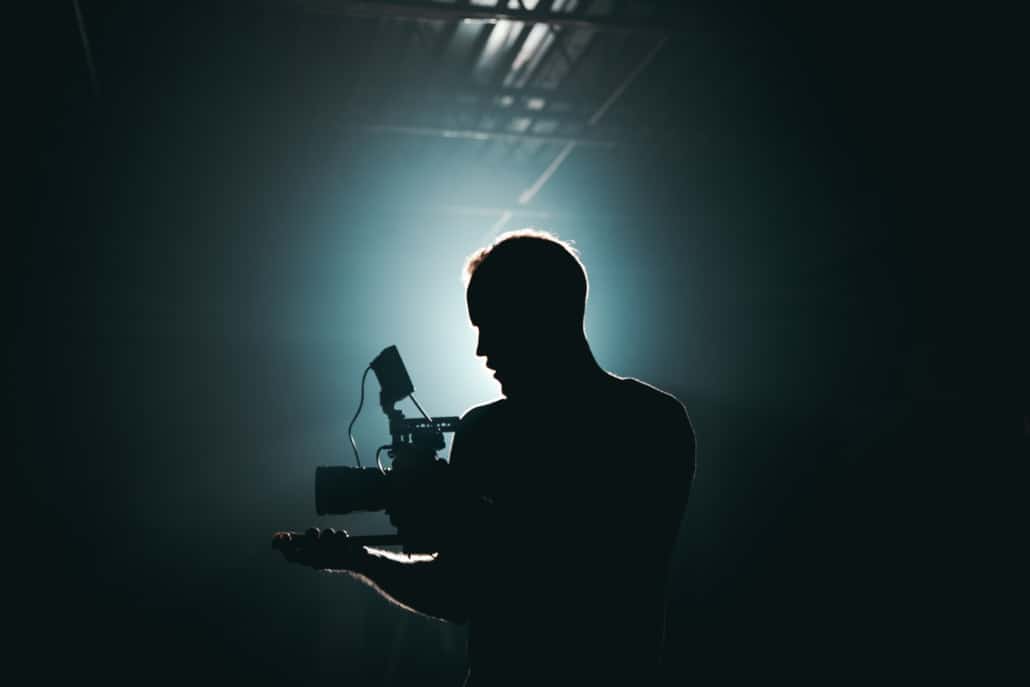 Die Silhouette eines Mannes mit einer Kamera in einem dunklen Raum.