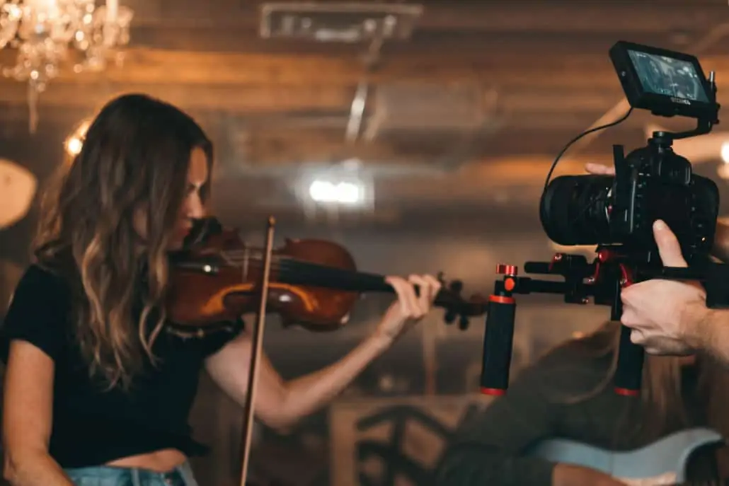 Eine Frau spielt Geige, während ein Mann sie filmt.