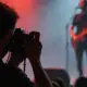 Konzertfotograf im Fotograben fotografiert eine Band bei farbigem Bühnenlicht